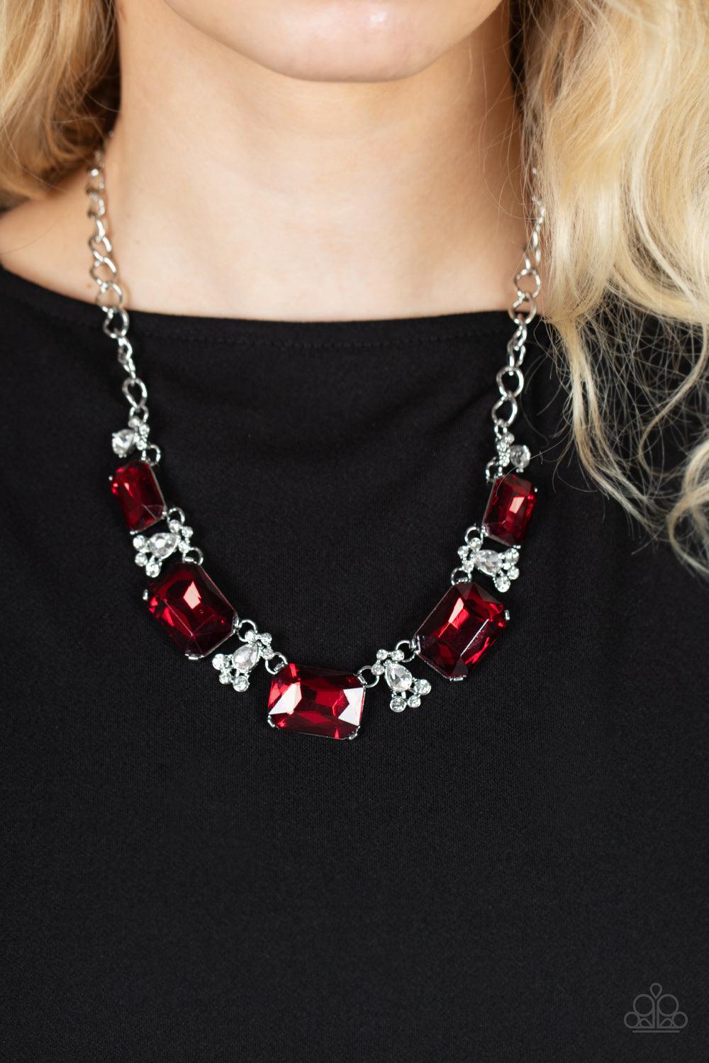 Paparazzi Accessories Flawlessly Famous - Red Featuring a fiery finish, an oversized collection of emerald cut red rhinestones link with rhinestone dotted teardrop rhinestone frames below the collar for a jaw-dropping display. Features an adjustable clasp