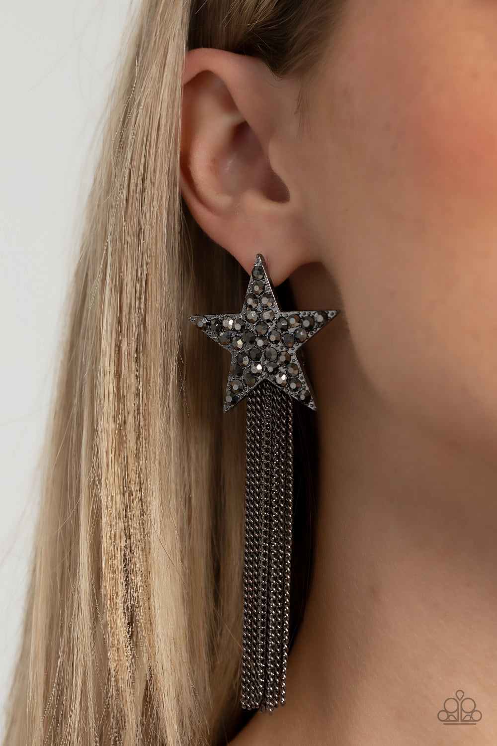 Paparazzi Accessories Superstar Solo - Black A curtain of gunmetal chains streams out from the bottom of an oversized gunmetal star encrusted in smoky hematite rhinestones, resulting in a stellar tassel. Earring attaches to a standard post fitting. Sold a