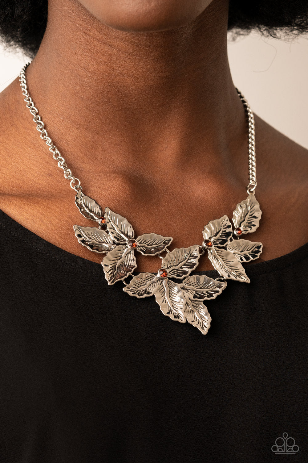 Paparazzi Accessories Holly Heiress - Brown A textured collection of silver holly-like leaves are dotted with dainty topaz rhinestones as they bloom below the collar, invoking a festive spirit. Features an adjustable clasp closure. Sold as one individual