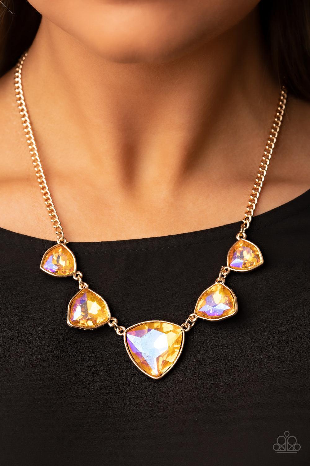 Paparazzi Accessories Cosmic Constellations - Gold Encased in sleek gold fittings, an oversized collection of UV geometric gems gradually increase in size as they link below the collar for a golden statement. Features an adjustable clasp closure. Sold as
