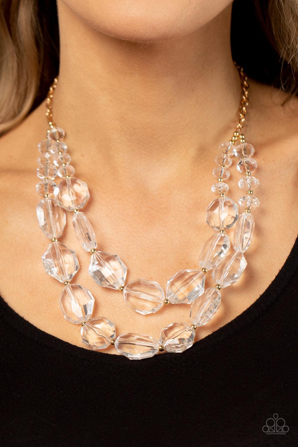 Paparazzi Accessories Icy Illumination - Gold Separated by dainty gold beads, an icy collection of oversized and faceted white gems are threaded along invisible wires below the collar, resulting in prismatic layers. Features an adjustable clasp closure. S