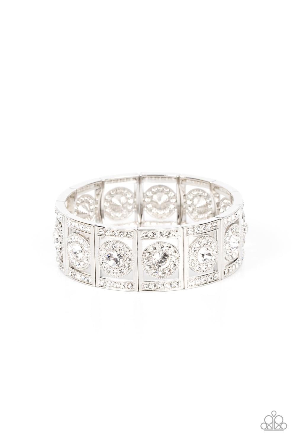 Paparazzi Accessories Ultra Upscale - White A glassy white rhinestone is pressed into a ring of glitzy white rhinestones inside a rectangular silver frame dusted in dazzling white rhinestones. The timeless frames sparkle along stretchy bands around the wr