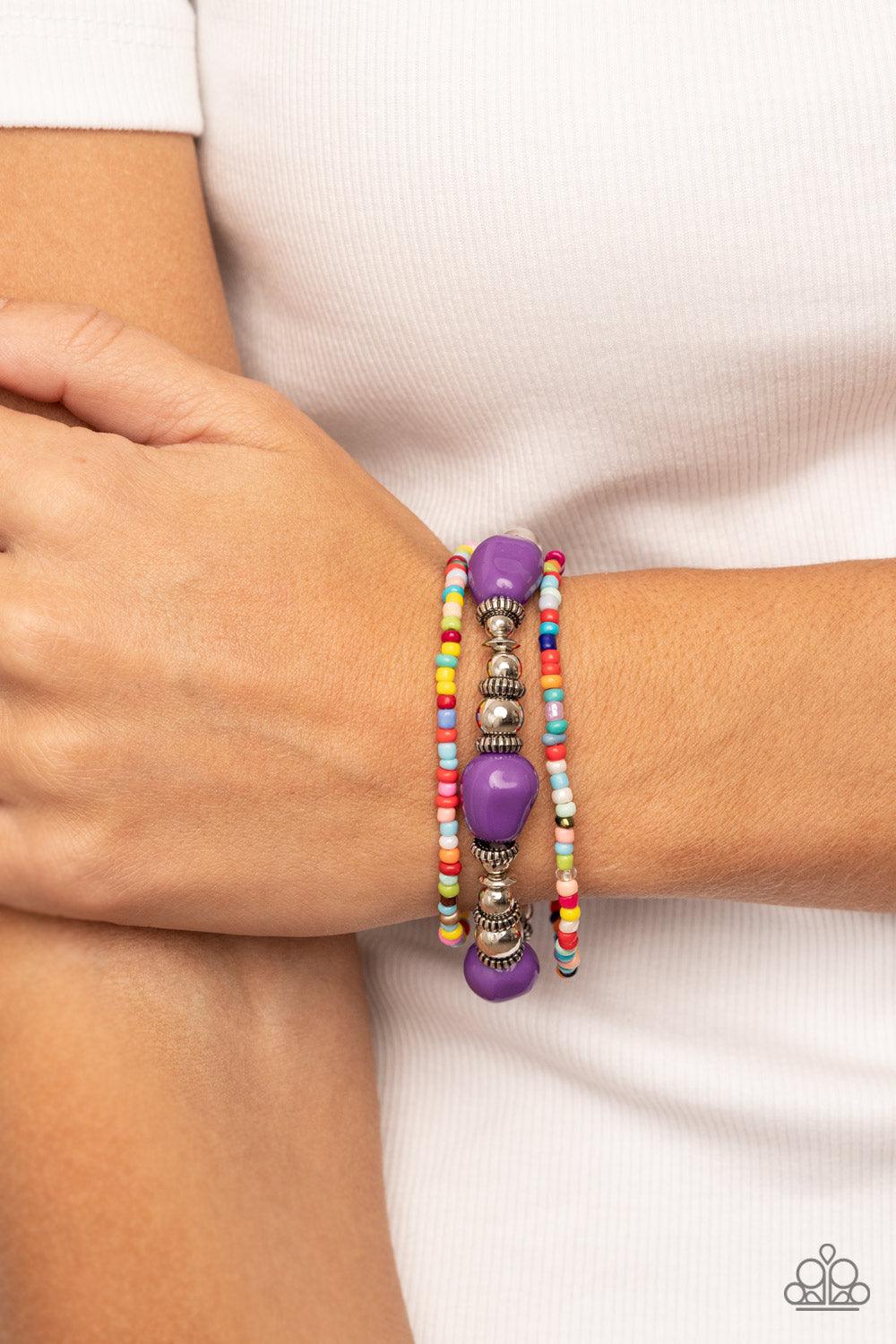 Paparazzi Accessories Confidently Crafty - Purple A pair of multicolored seed beaded stretchy bracelets joins a stretchy strand of shiny silver beads, textured silver accents, and faceted purple beads around the wrist, creating colorful layers. Sold as on
