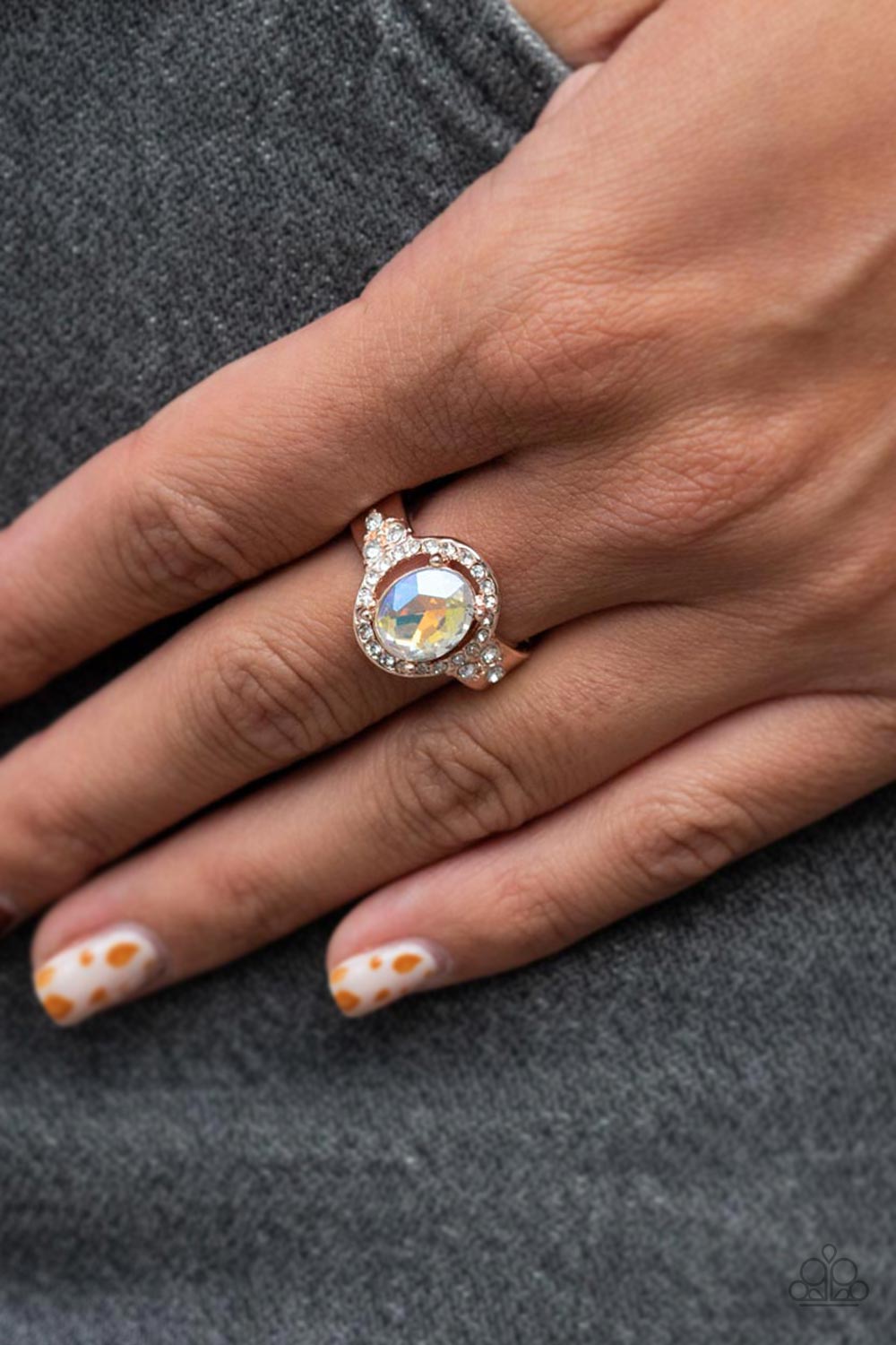 Paparazzi Accessories Dazzling I Do’s - Rose Gold Reminiscent of an engagement ring, an iridescent oval gem is showcased atop a white rhinestone encrusted rose gold setting for an elegantly stellar finish. Features a dainty stretchy band for a flexible fi