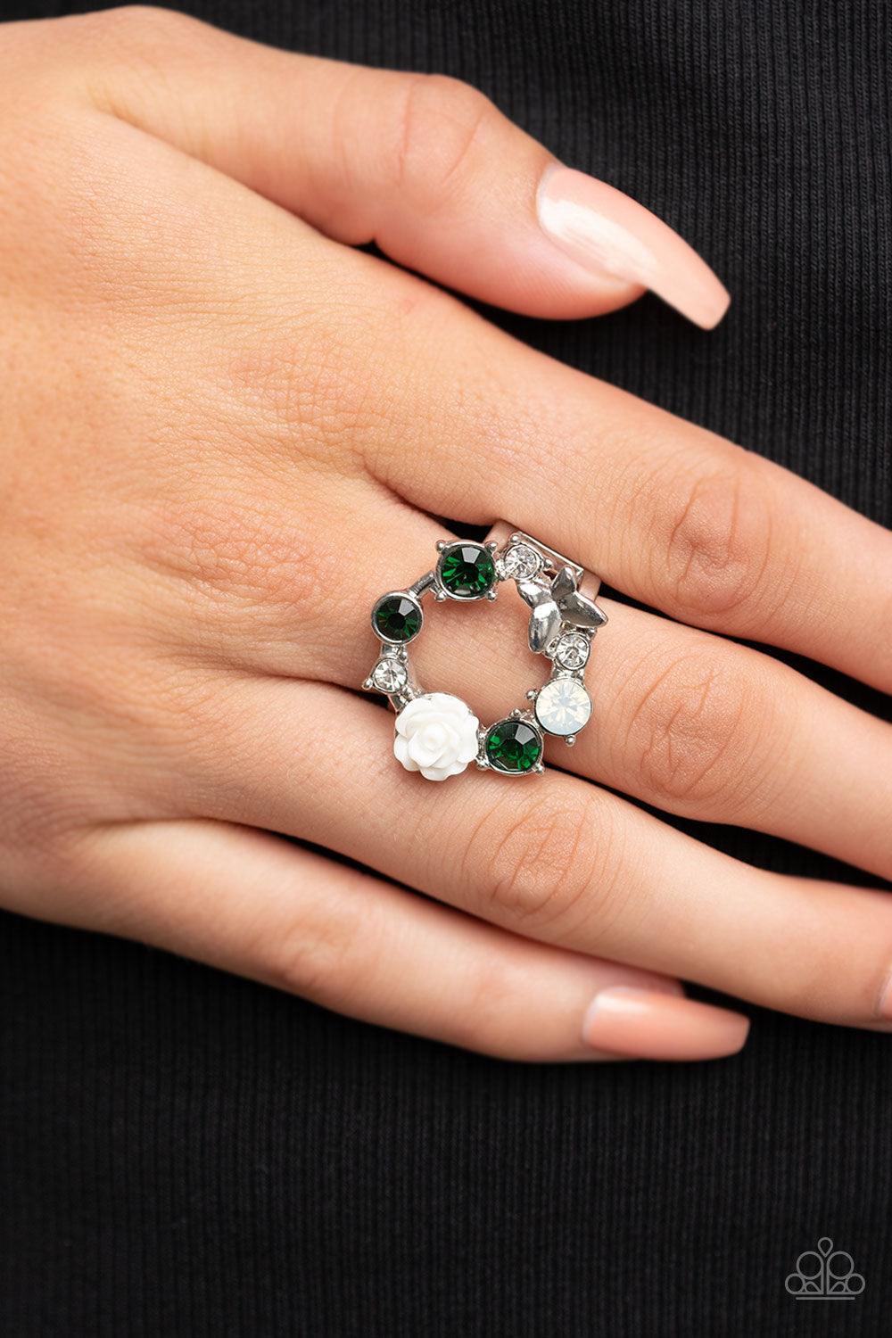 Paparazzi Accessories Butterfly Bustle - Green A glitzy collection of green, opal, and white rhinestones coalesce into a sparkly wreath atop the finger. Elegantly enhanced with a white resin rosebud, a dainty silver butterfly flutters atop the glittery ce