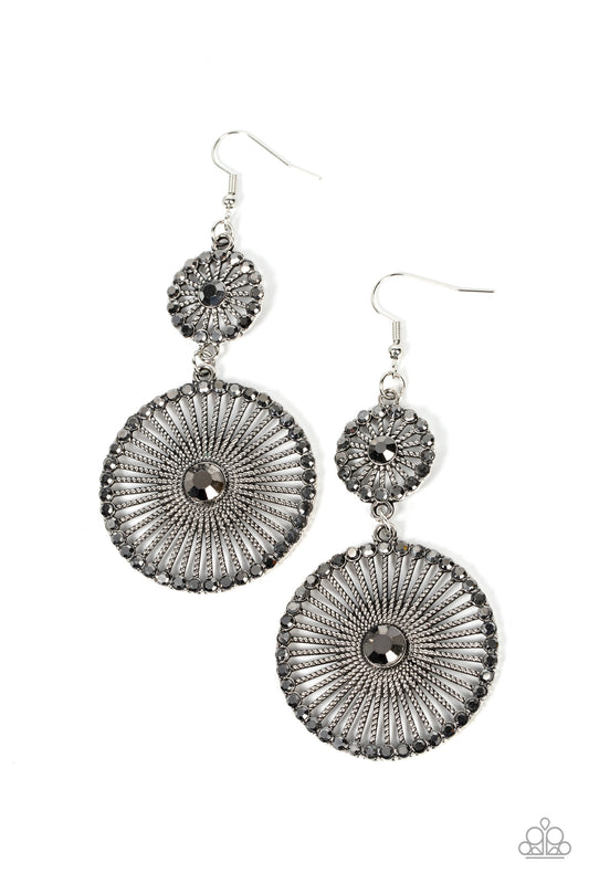 Paparazzi Accessories Bring Down the WHEELHOUSE - Silver Bordered in dainty hematite rhinestones and adorned with oversized hematite rhinestone centers, a pair of silver frames radiating with textured silver spokes links into a dizzying lure for an edgy s