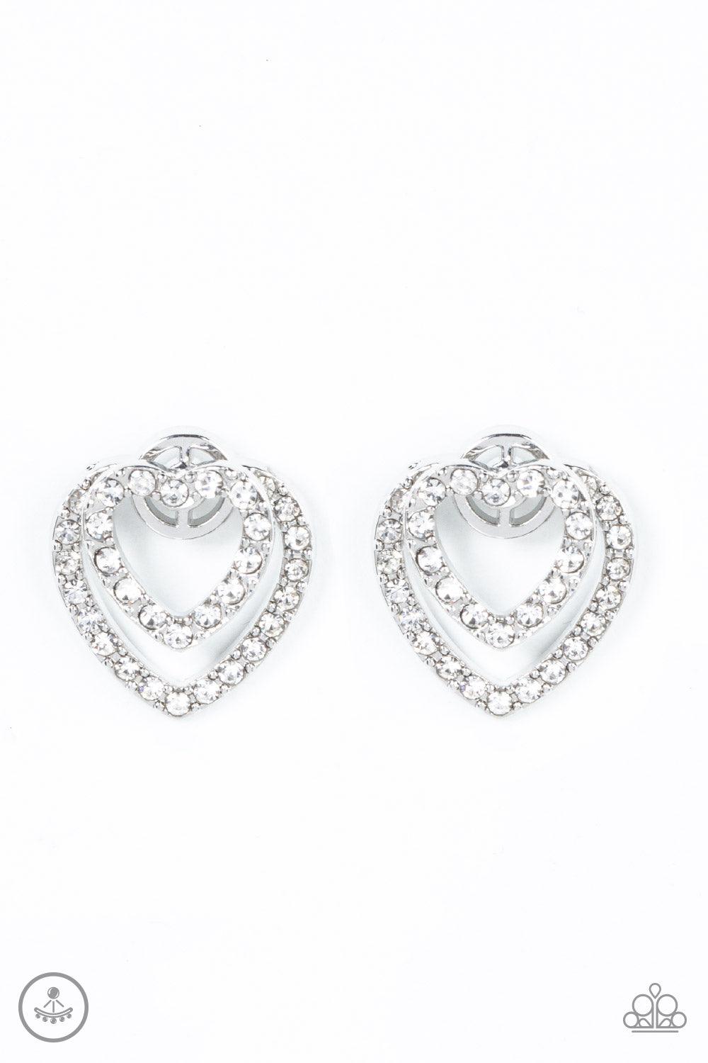 Paparazzi Accessories Ever Enamored - White A dainty silver heart dotted in glassy white rhinestones flirtatiously attaches to a double-sided post, while a slightly larger white rhinestone encrusted silver heart peeks out beneath the ear for a romantic fi