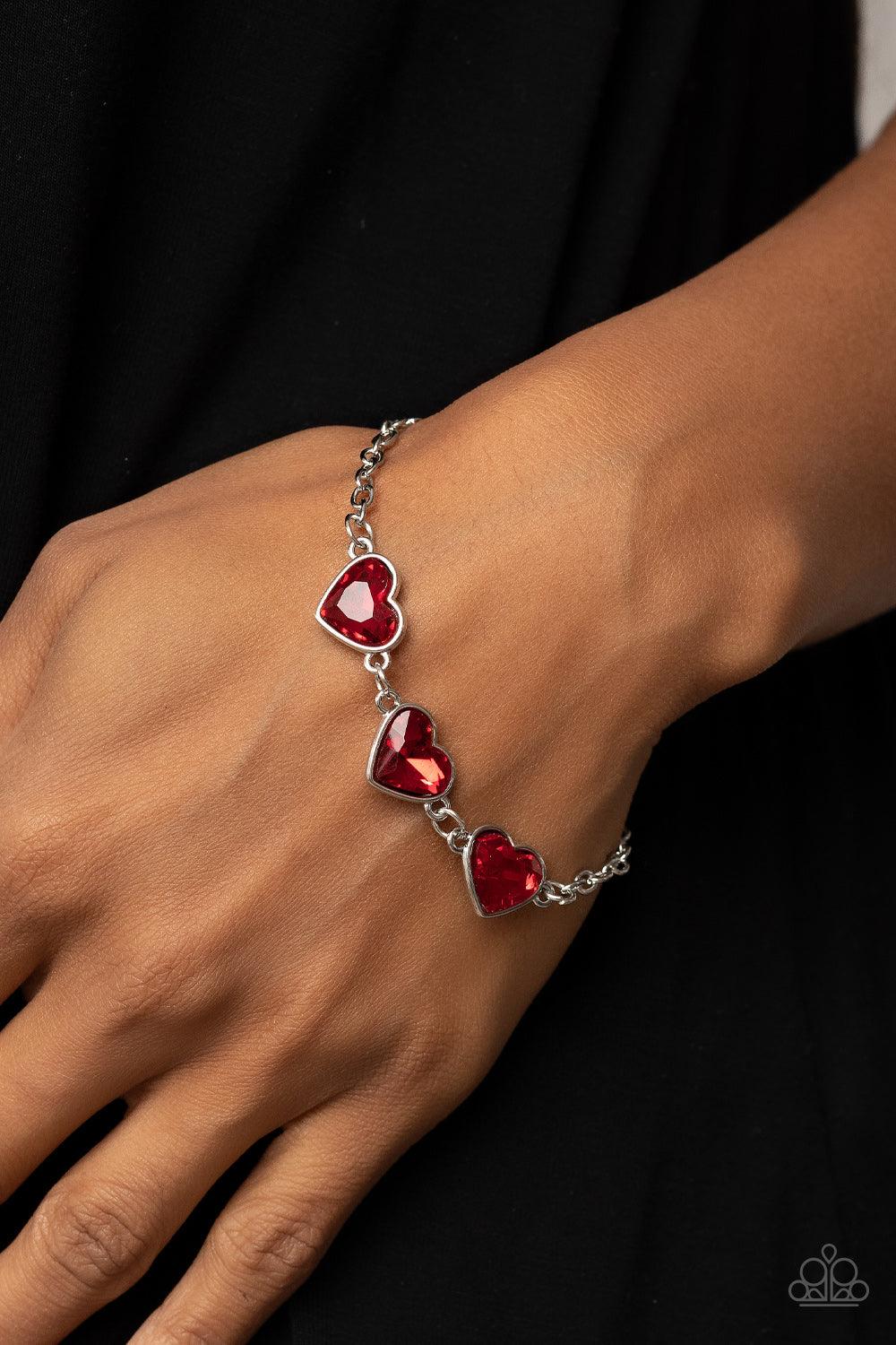 Paparazzi Accessories Little Heartbreaker - Red Nestled in silver frames, a trio of glittery red heart-shaped gems delicately links across the wrist for a dash of swoon-worthy shimmer. Features an adjustable clasp closure. Sold as one individual bracelet.