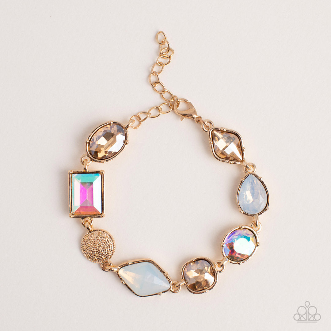 Paparazzi Accessories Jewelry Box Bauble - Gold Encased in pronged gold fittings, a mismatched collection of golden, iridescent, and opal rhinestones delicately links with a studded gold frame around the wrist for a sentimental sparkle. Features an adjust