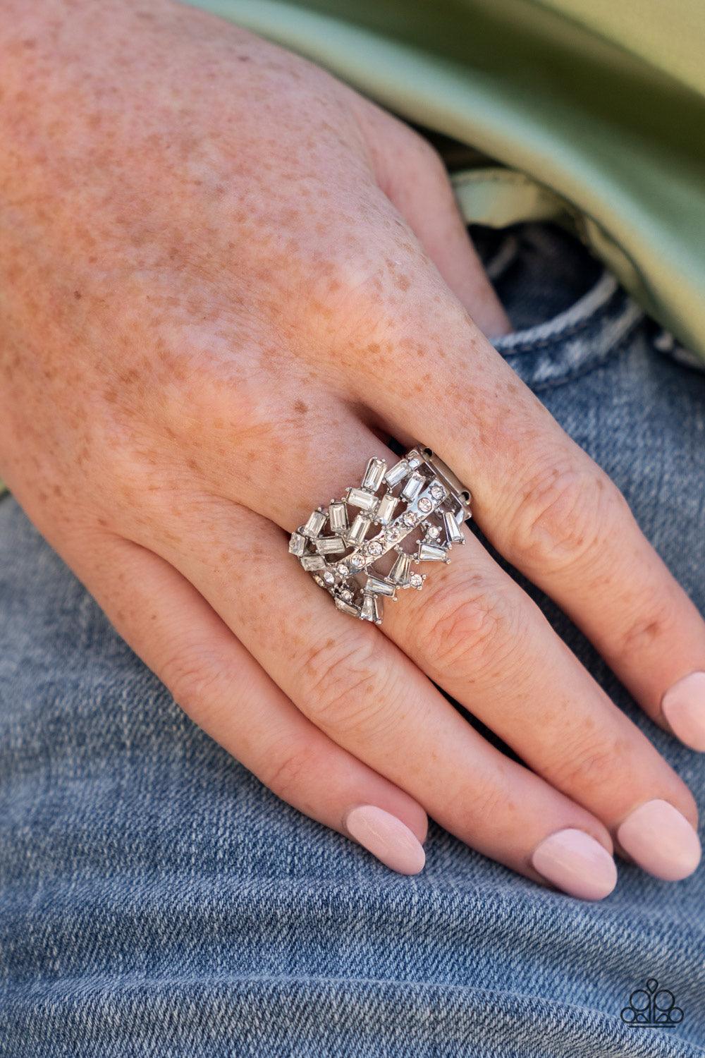 Paparazzi Accessories Scattered Sensation - White Dotted in dainty white rhinestones, a single silver band separates a haphazard explosion of round and emerald cut rhinestones across the finger. Features a stretchy band for a flexible fit. Sold as one ind