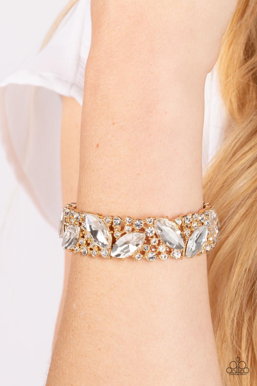 Paparazzi Accessories Full Body Chills - Gold Oversized marquise cut white rhinestones sparkle atop icy frames of dainty gold studs and white rhinestones that are threaded along stretchy bands around the wrist for a jaw-dropping dazzle. Sold as one indivi