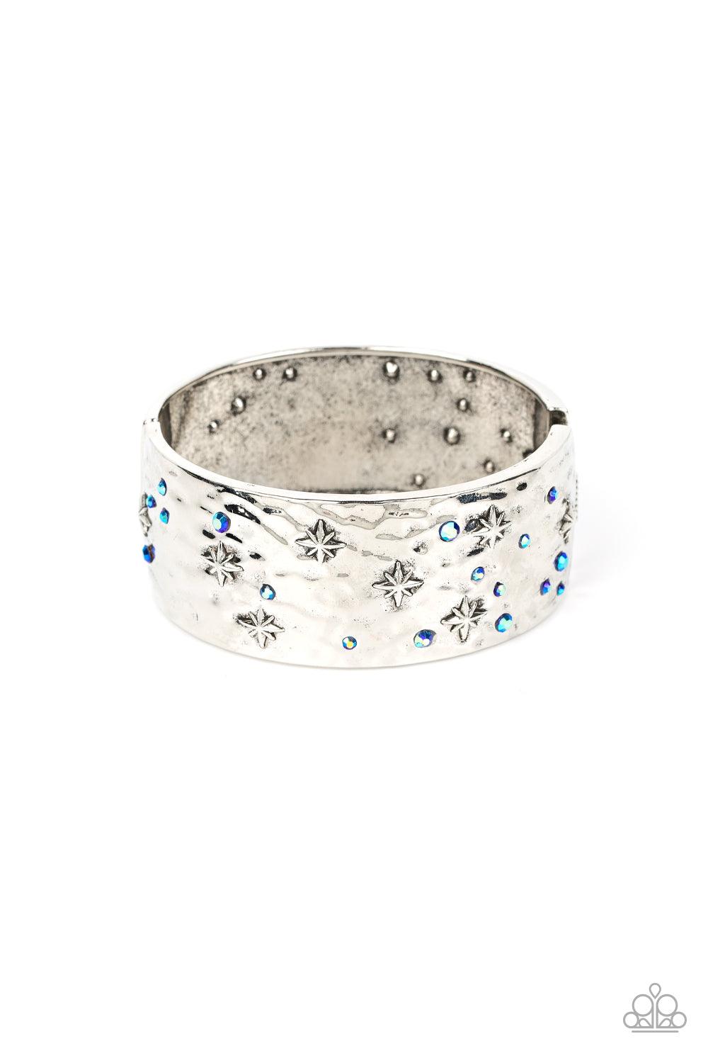 Paparazzi Accessories Across the Constellations - Blue Twinkling with dainty silver stars, hammered silver frames are adorned with a smattering of iridescent blue rhinestones as they delicately join into a bangle-like bracelet around the wrist. Due to its