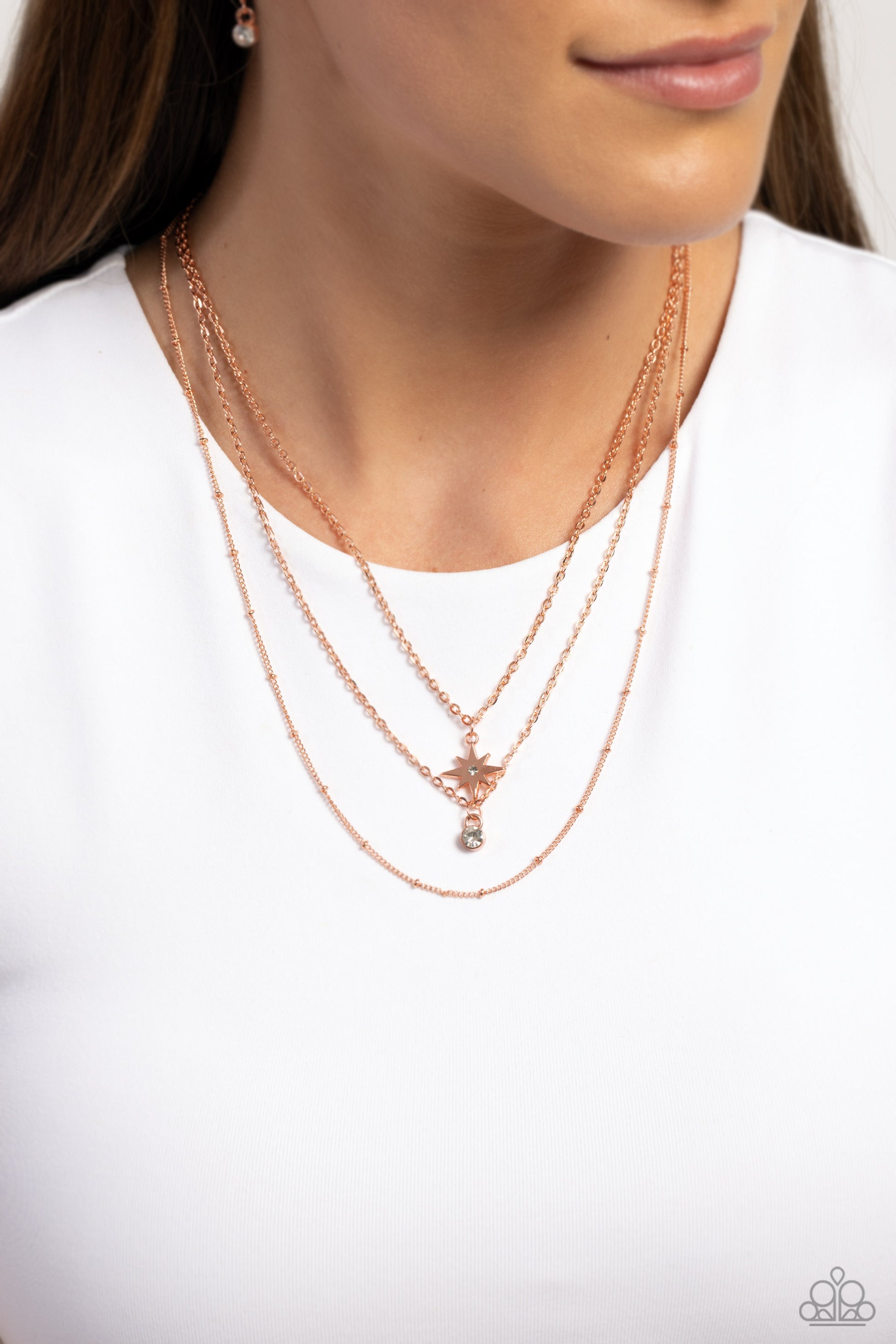 Paparazzi Accessories Trendy Twinkle - Copper Three mismatched shiny copper chains layer across the chest. Dotted in a dainty white rhinestone, a shiny copper charm swings from the uppermost chain above a solitaire white rhinestone for a twinkly finish. F
