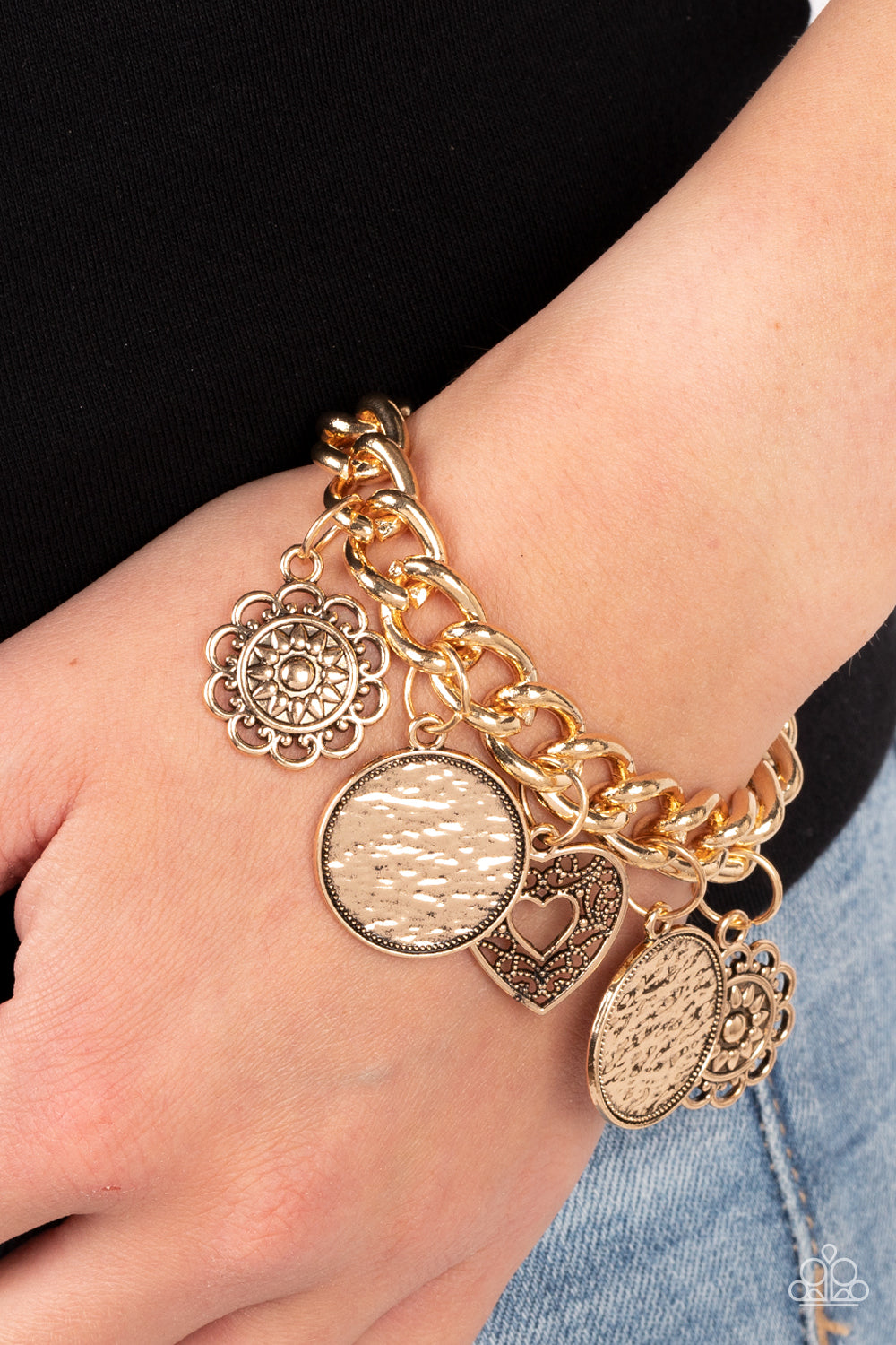 Paparazzi Accessories Complete CHARM-ony - Gold A whimsical collection of gold charms — including an airy heart, flowers, and textured coin-like discs — dance from a chunky gold chain around the wrist, creating a boisterous fringe. Features an adjustable