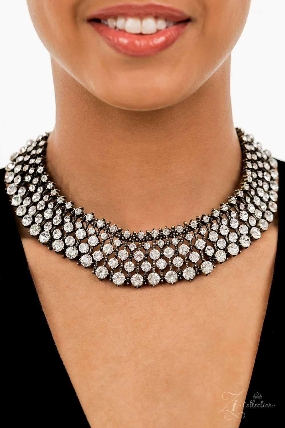 Paparazzi Accessories Undeniable Thin bars of brass, etched in rugged linear texture and dotted with tiny brass studs, are topped by brilliant white rhinestones encased in pronged fittings. The bars are threaded along wires and separated by tiny brass bea