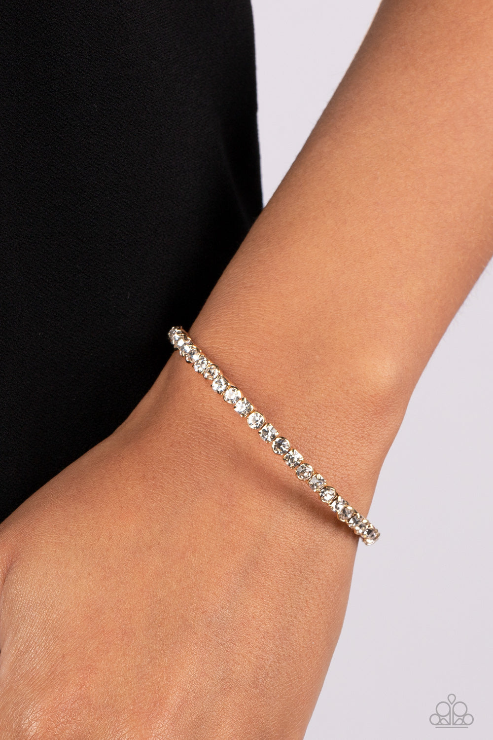 Paparazzi Accessories Rhinestone Spell - Gold Set in simple square and circular gold fittings, a sparkly strand of icy white rhinestones delicately curls around the wrist, resulting in a spellbinding cuff-like bracelet. Sold as one individual bracelet. Je
