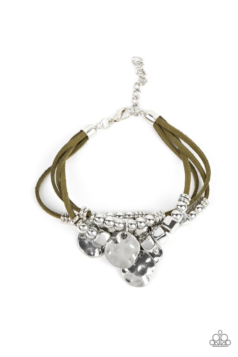 Paparazzi Accessories Token Trek - Green Asymmetrical, hammered silver discs swing from layers of Martini Olive suede that are adorned with silver discs, beads, and cubes, resulting in noisemaking shimmer around the wrist. Features an adjustable clasp clo