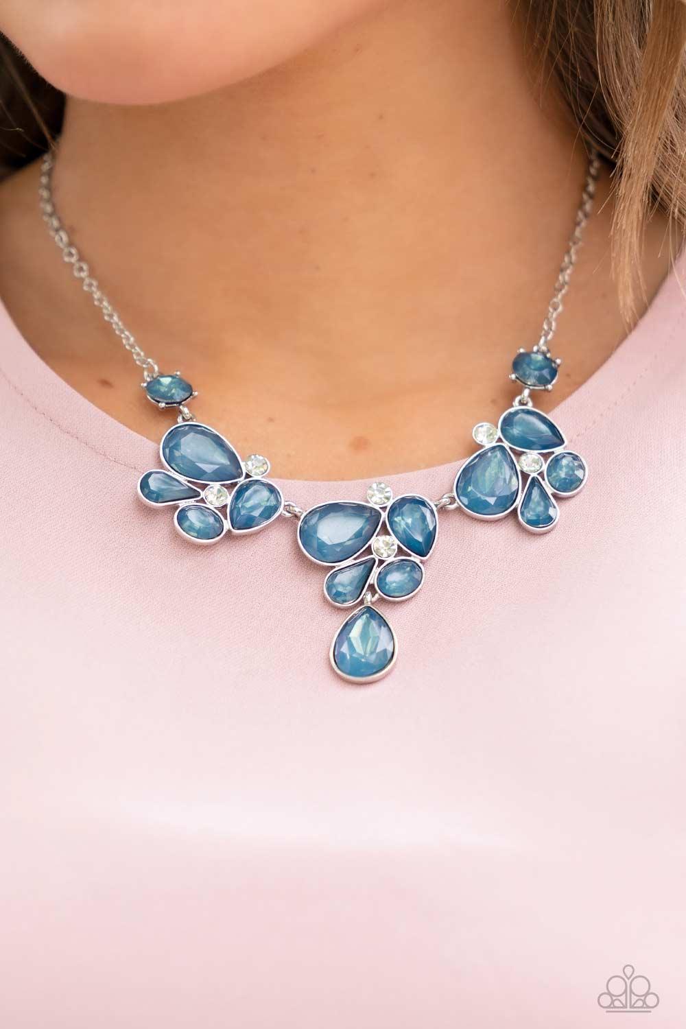 Paparazzi Accessories Everglade Escape - Blue Draped elegantly across the chest, clusters of geometric blue gems, brushed in the fall Pantone® of Midnight, gather around sparkling white rhinestones, creating a bright and beautiful pattern. Features an adj