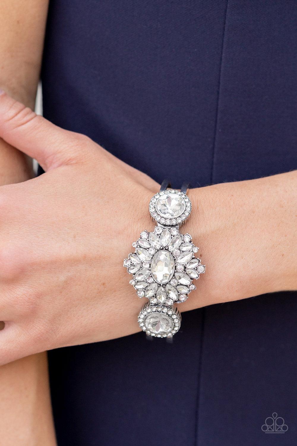 Paparazzi Accessories Daydream Dazzle - White A decadent explosion of dainty white rhinestones and teardrop gems frame a reflective oval gem at their center. On either side of the shimmery centerpiece dainty white rhinestones encircle reflective white gem