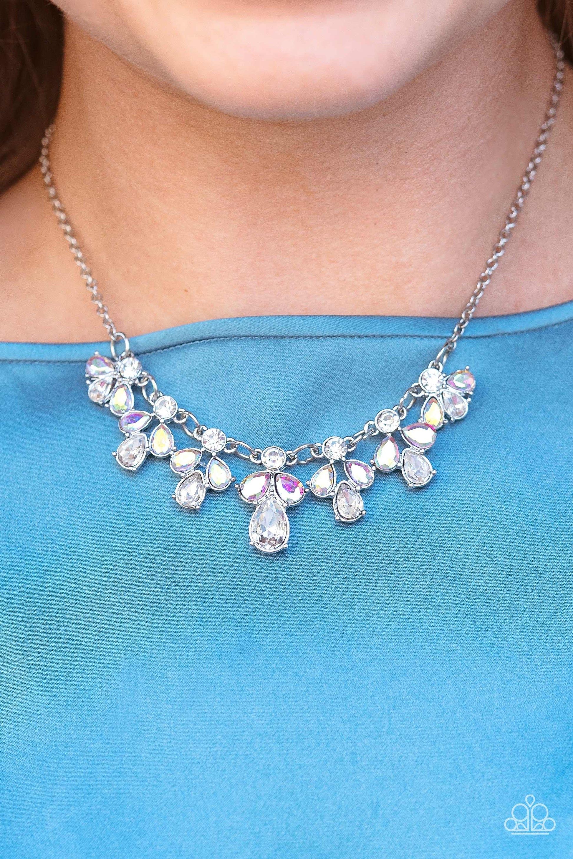 Paparazzi Accessories See in a New STARLIGHT - White Dainty white reflective gems, followed by a trio of iridescent and reflective teardrop gems vertically blaze down the collar, creating a starry shimmer. Due to its prismatic palette, color may vary. Fea