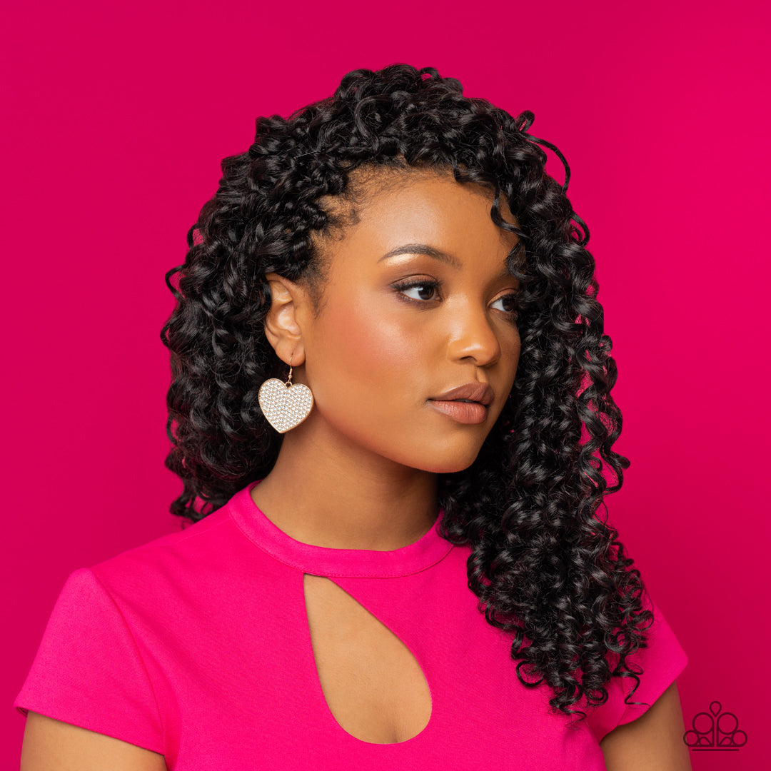 Paparazzi Accessories Romantic Reign - Gold A shiny, oversized gold heart is covered in tiny white rhinestones, emitting radiant shimmer as it swings from the ear. Earring attaches to a standard fishhook fitting. Sold as one pair of earrings. Jewelry