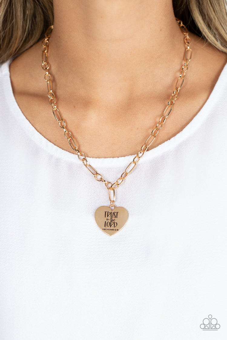 Paparazzi Accessories Perennial Proverbs - Gold Dangling from a gold figaro chain, a charming heart pendant swings. Stamped upon the shiny surface, the phrase "Trust in the Lord" with the bible reference listed below it "Proverbs 3:5" are listed in differ
