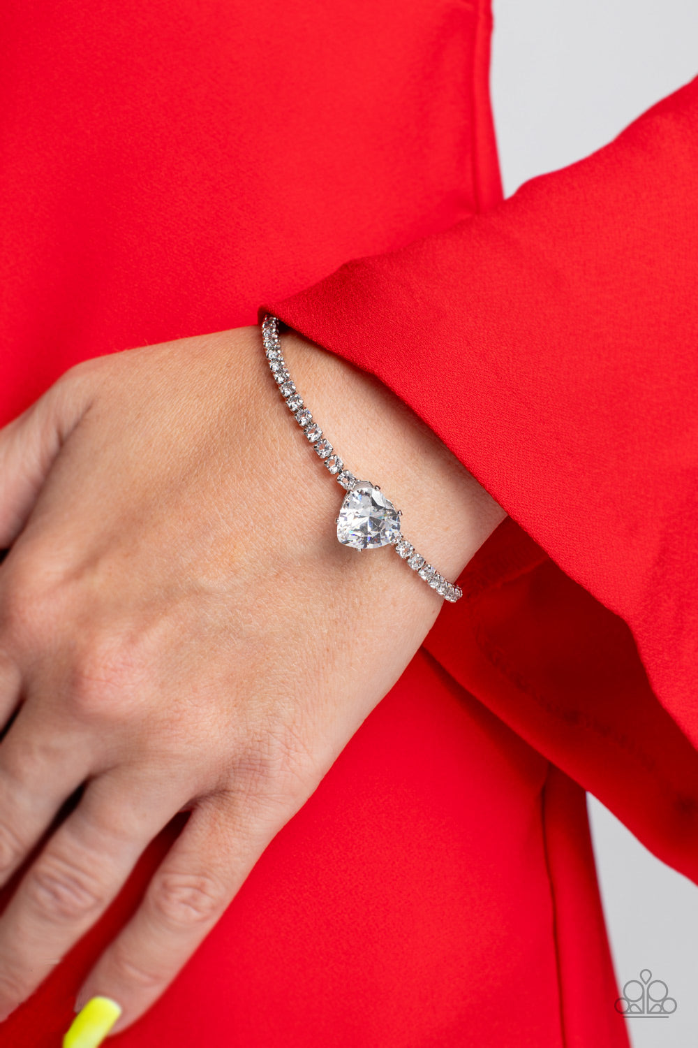 Paparazzi Accessories Bedazzled Beauty - White An oversized white heart-shaped gem, set in an airy, pronged silver fitting, glitters at the center of a blinding row of dainty, glassy white rhinestones set in square silver fittings, resulting in a flirtati