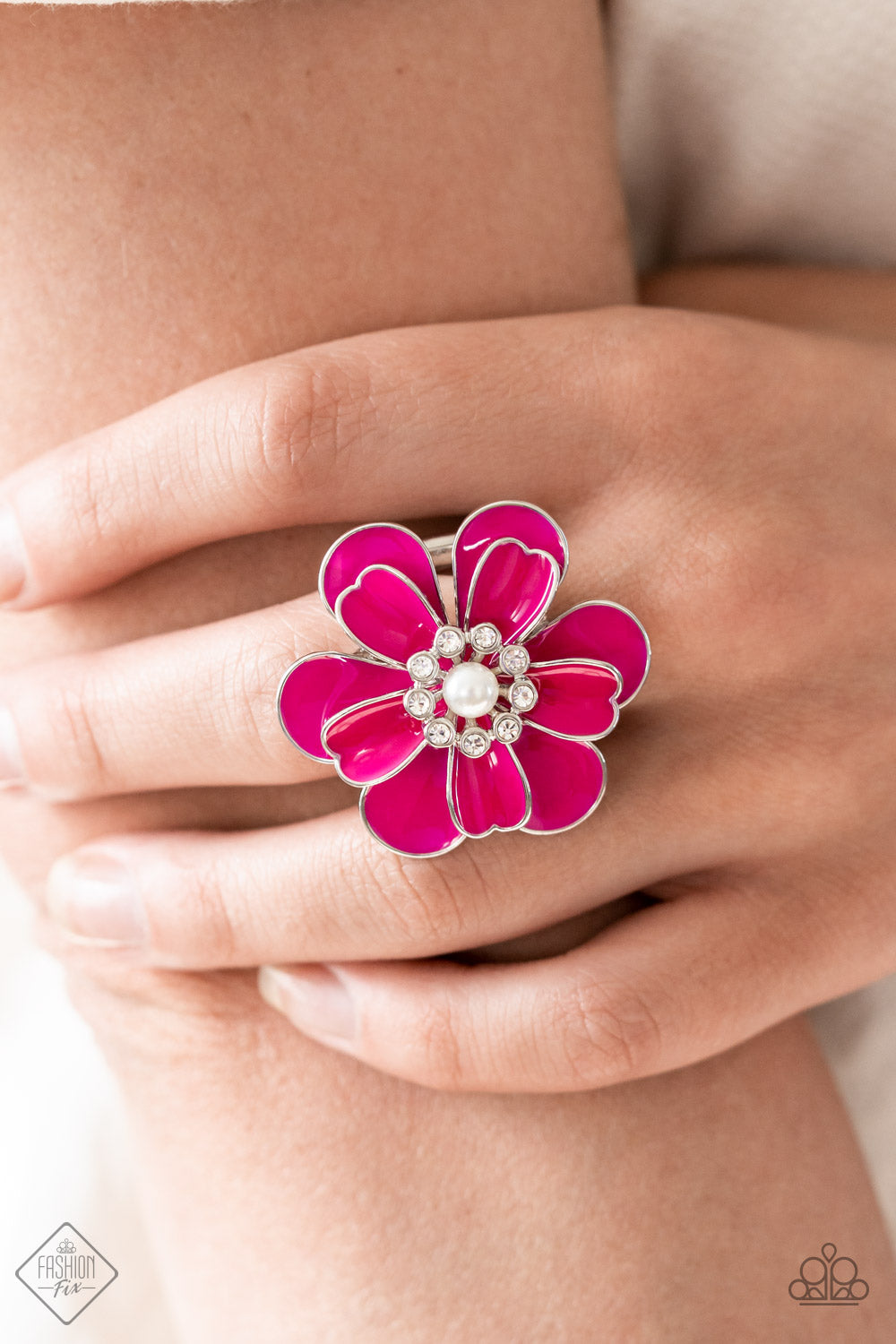 Paparazzi Accessories Budding Bliss - Pink An exaggerated pink flower with layers of petals blooms atop the finger in a vibrant display. A white pearl encircled by tiny white rhinestones adds a touch of whimsical sparkle to the design. Features a stretchy