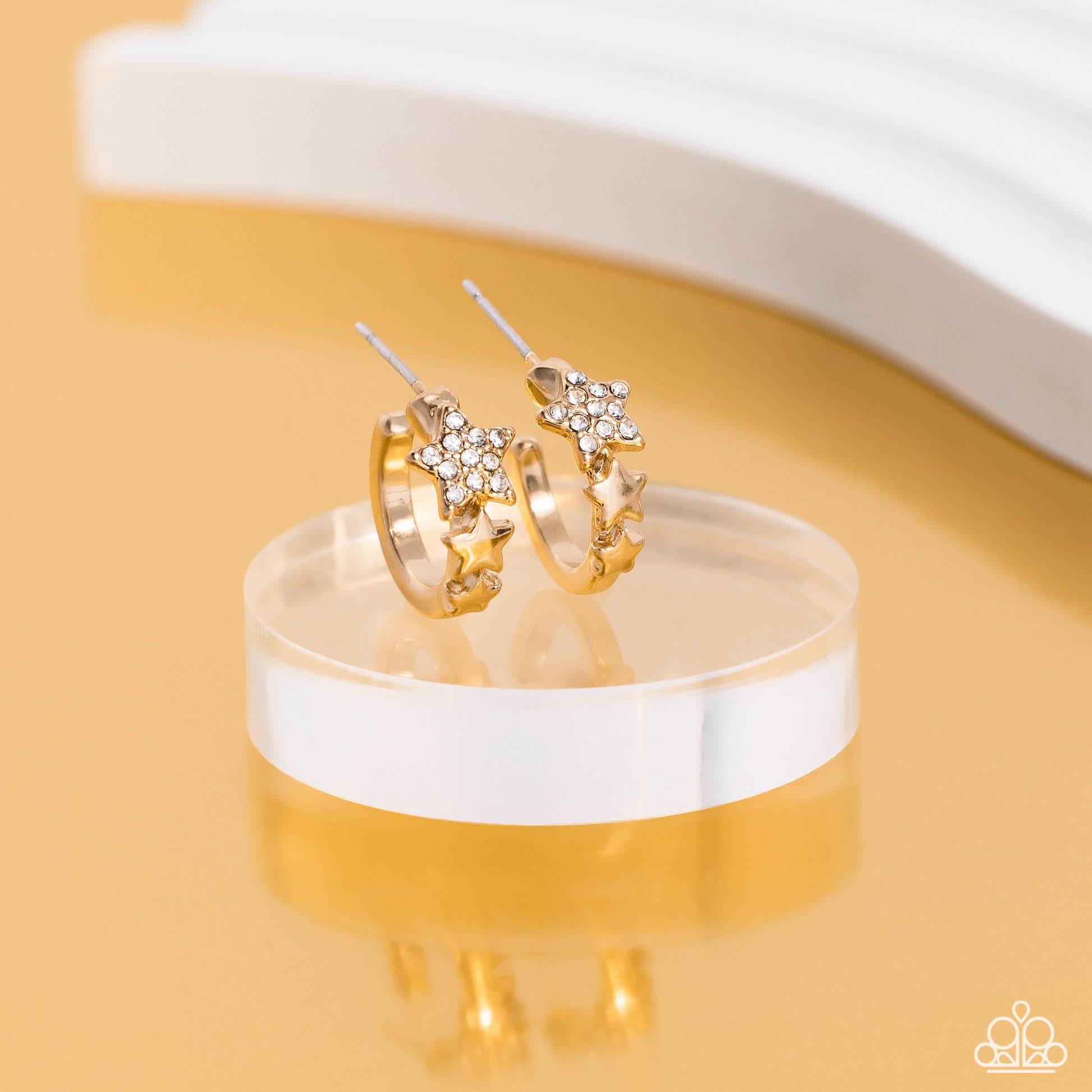 Paparazzi Accessories Starfish Showpiece - Gold A shiny gold bar curls around the ear into a dainty hoop. Three gold stars gradually increase in size as they climb the curve of the hoop, with the biggest star emblazoned with white crystal-like rhinestones