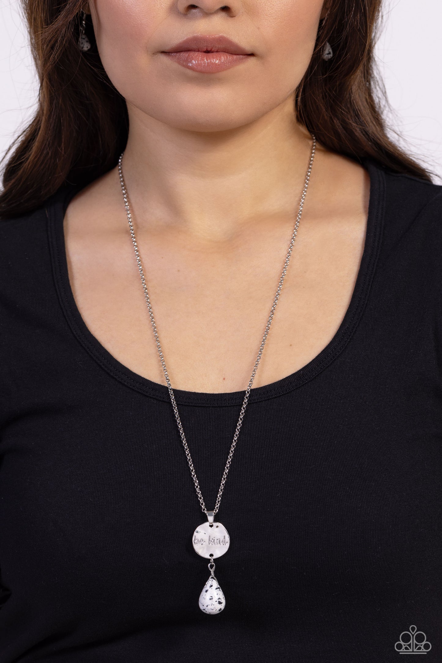 Paparazzi Accessories Caring Couture - White Swinging from a dainty silver chain, a hammered disc in the same hue is stamped with the words "be kind." A chiseled white speckled teardrop hangs from the bottom of the pendant adding a fashionably rustic feat