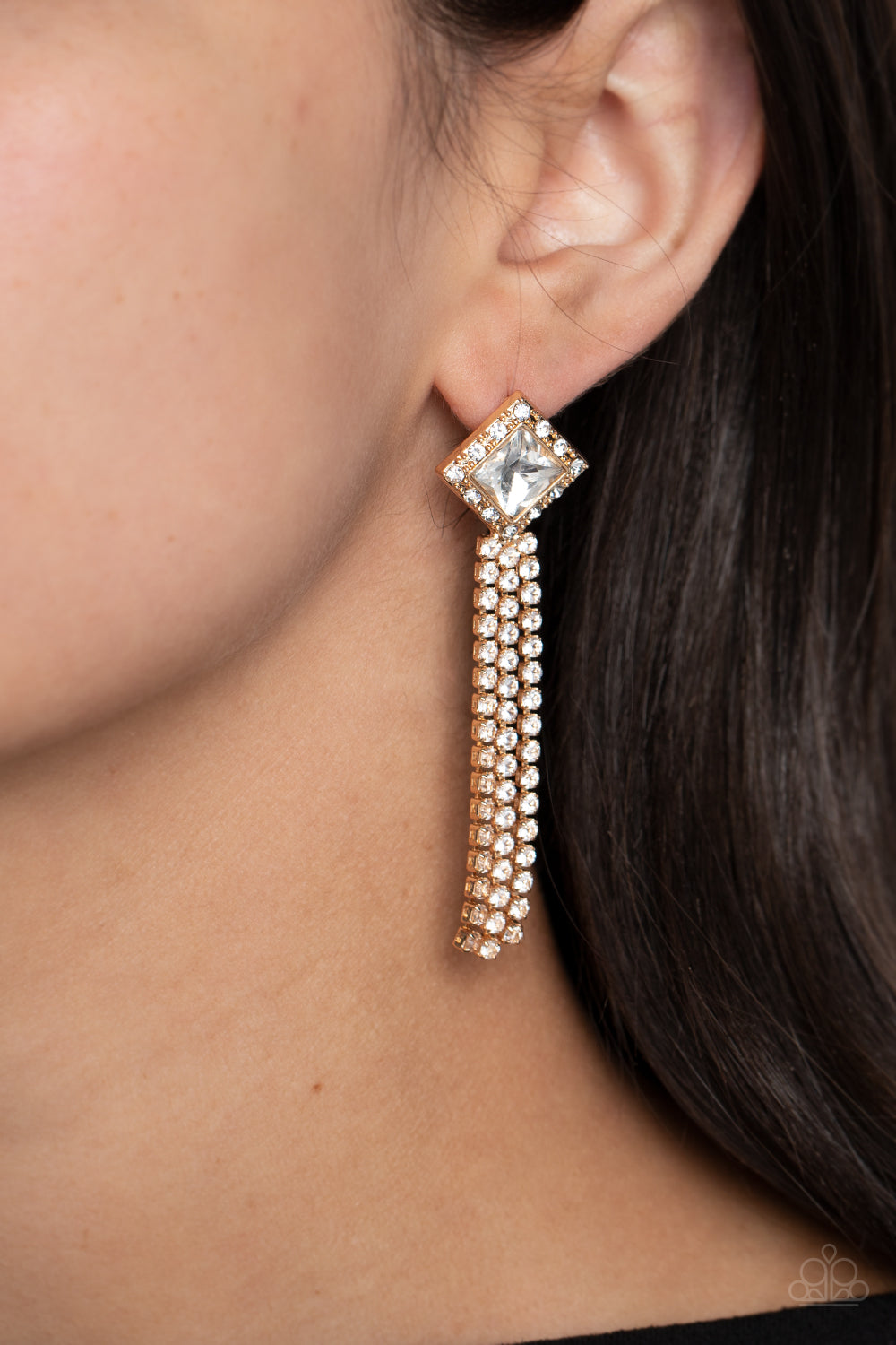 Paparazzi Accessories Seasonal Sparkle - Gold A brilliant, square-cut white rhinestone is bordered by tiny sparkling accents and tilted on a point against a gold backdrop, creating a dramatic anchoring point from which streams of glittery, square-cut rhin