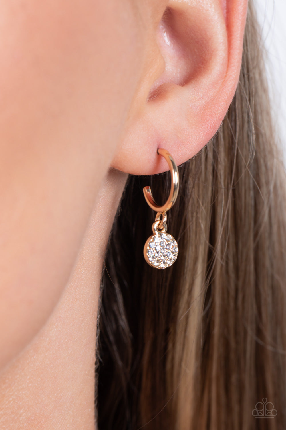 Paparazzi Accessories Bodacious Ballroom - Gold Swinging from a glistening gold hoop, a dainty gold disc, embossed with white rhinestones glimmers, adding a subtle shimmer around the ear. Earring attaches to a standard post fitting. Hoop measures approxim