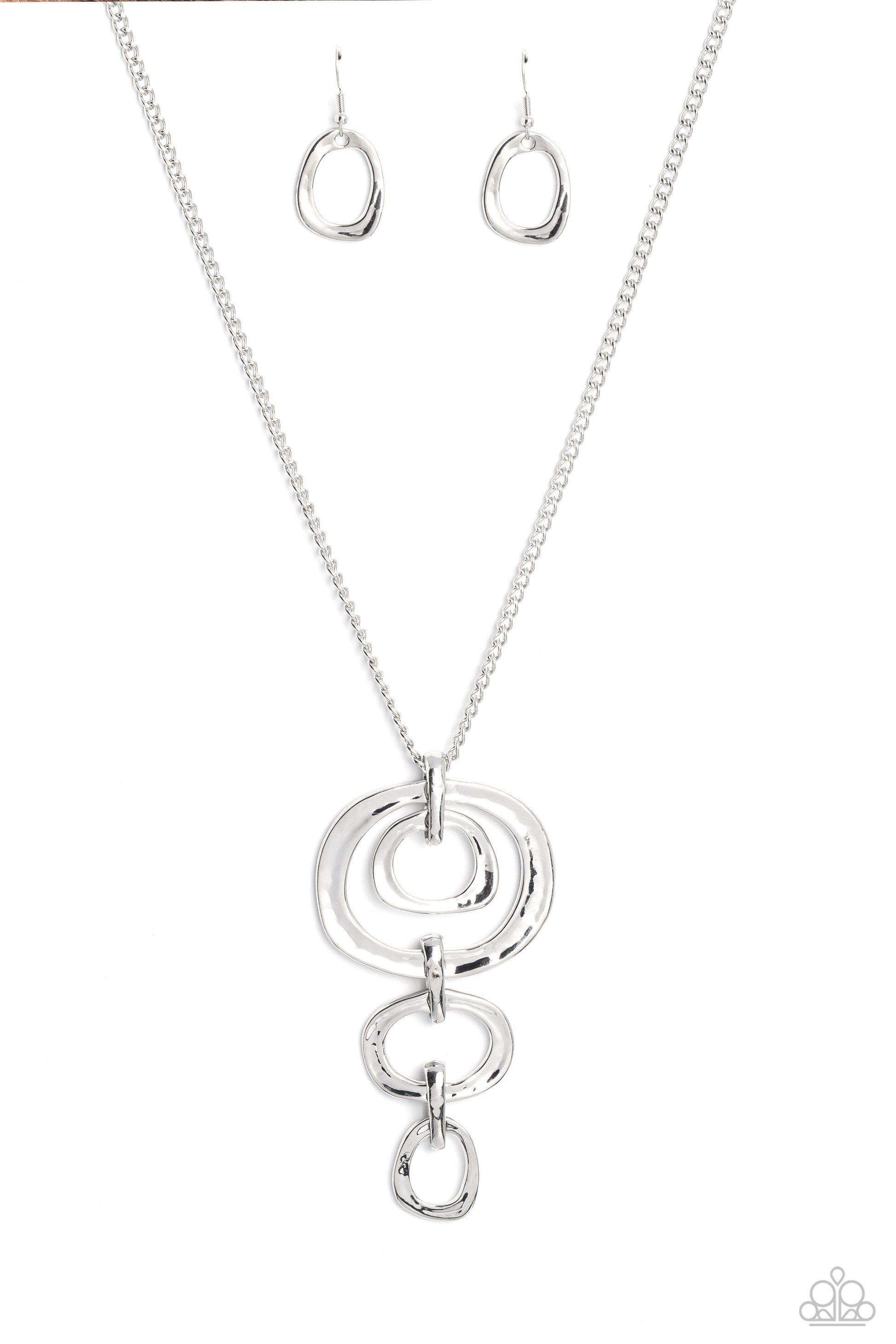 Paparazzi Accessories Tranquil Trickle - Silver Trickling down the chest from an elongated silver chain, a mismatched assortment of hammered silver abstract rings glistens in this monochromatic masterpiece. Features an adjustable clasp closure. Sold as on
