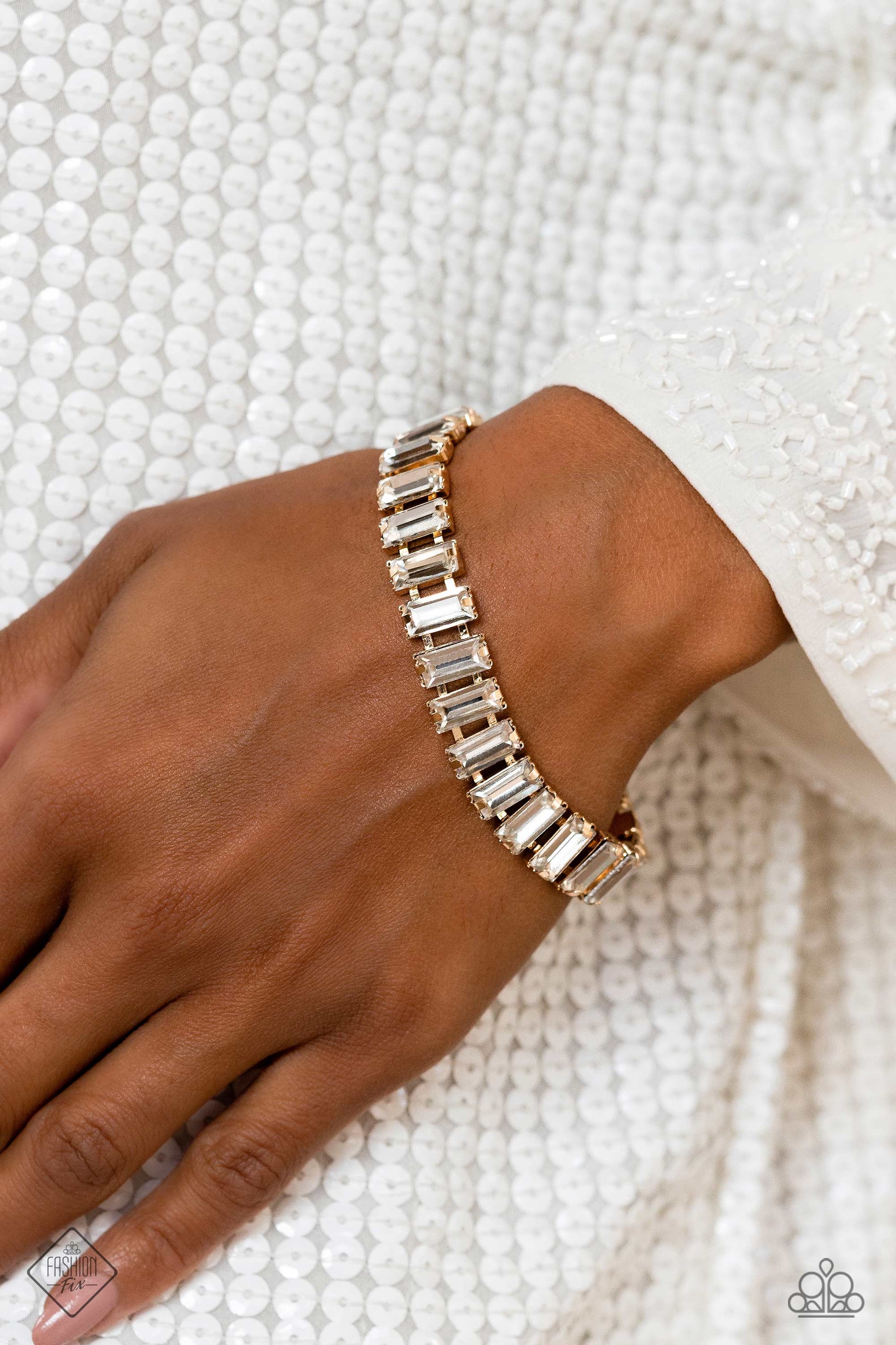 Paparazzi Accessories Darling Debutante - Gold Set in prominent, pronged gold fittings, a glassy collection of emerald-cut, white gems fall in line around the wrist, creating a stunning, light-catching display. Features an adjustable clasp closure. Sold a