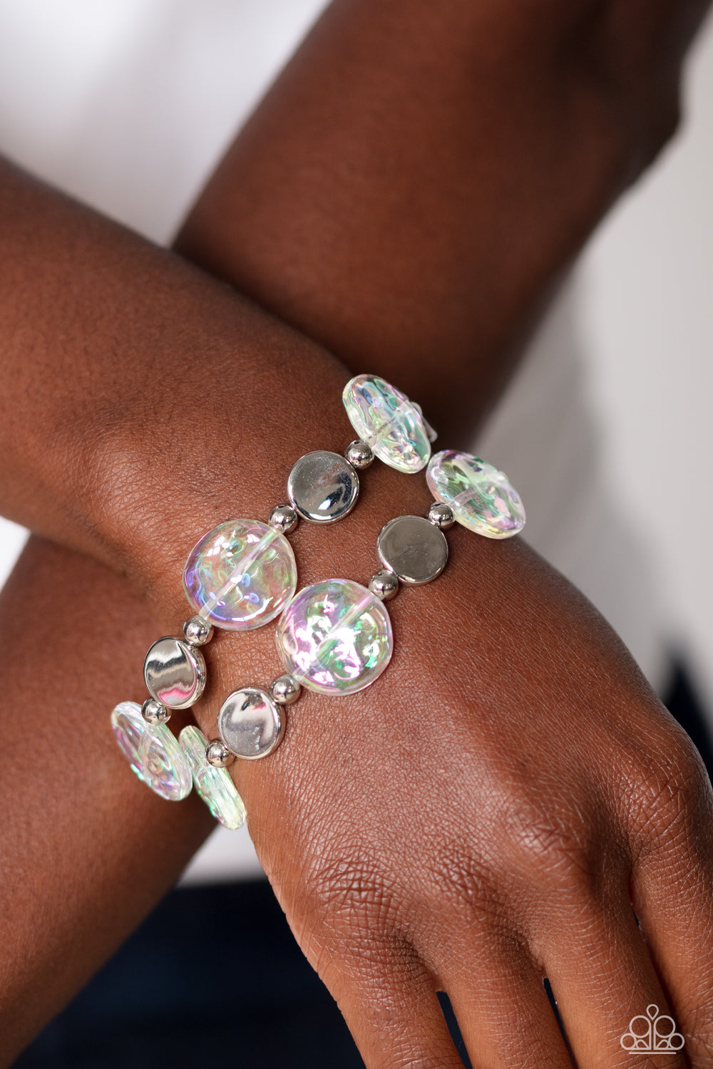 Paparazzi Accessories Discus Throw - White Shiny silver discs, studs, and asymmetrical clear discs featuring an iridescent shimmer coalesce around the wrist on elastic stretchy bands for an attention-grabbing shimmer. Due to its prismatic palette, color m