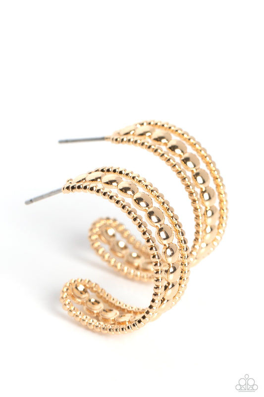 Paparazzi Accessories Dotted Darling - Gold A row of high-sheen gold studs runs down the center of an airy gold hoop for an edgy look. Layering against the centermost studs, smaller gold studs grace both sides of the hoop creating additional eye-catching