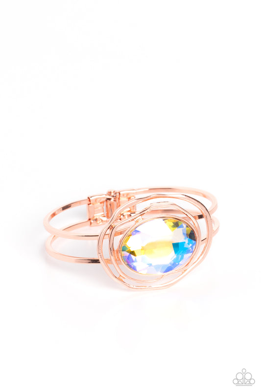 Paparazzi Accessories Substantial Sorceress - Copper Featured in the center of airy, shiny copper bands, an oversized, faceted iridescent oval gem rests atop the wrist for a dazzling pop of color. Warped, shiny copper rings seemingly float around the spar