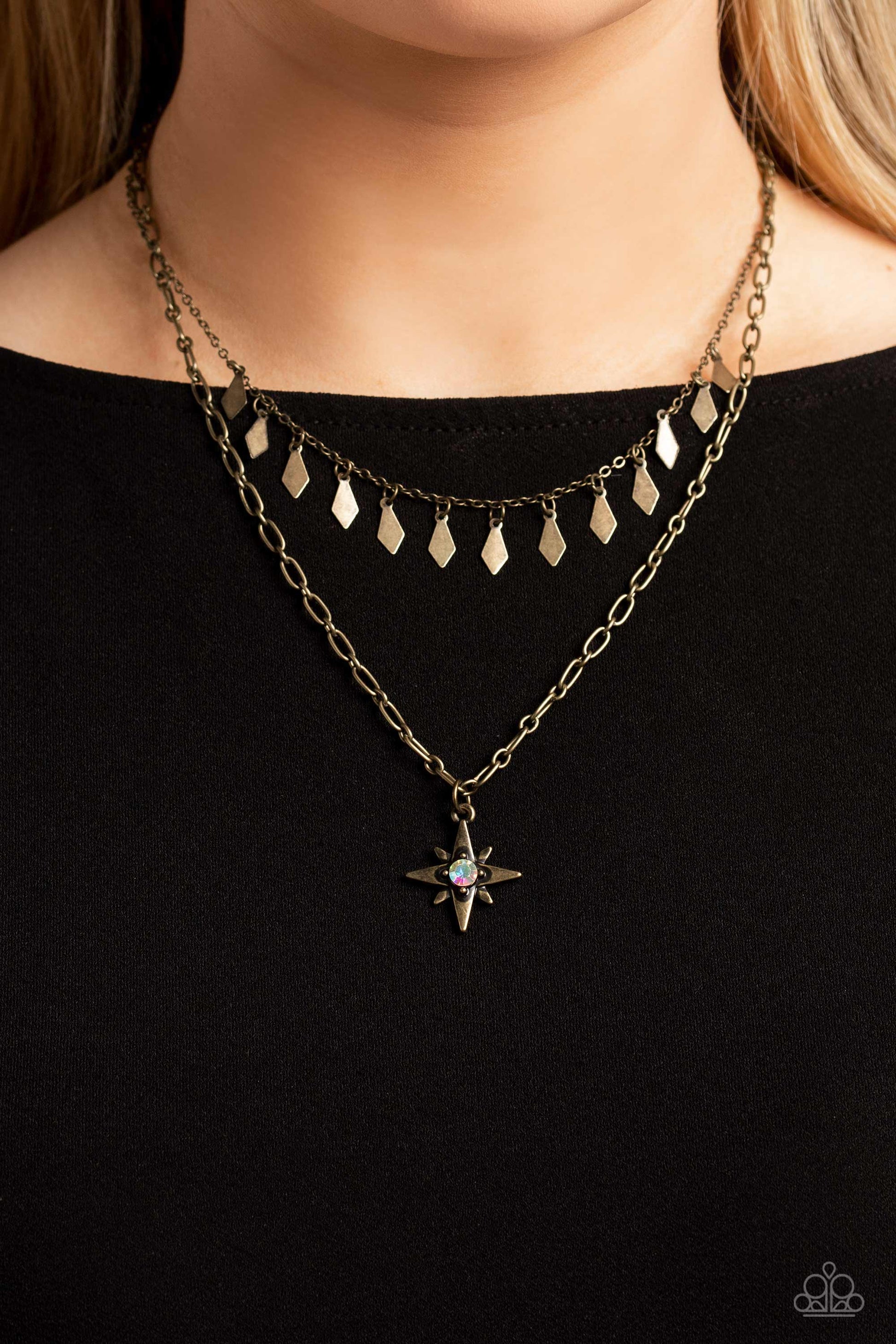 Paparazzi Accessories The Second Star To The LIGHT - Brass A three-dimensional brass star, dotted with a single iridescent rhinestone glides on a paperclip chain down the neckline for an out of-this-world-vibe. Flat and flared brass frames dance above the