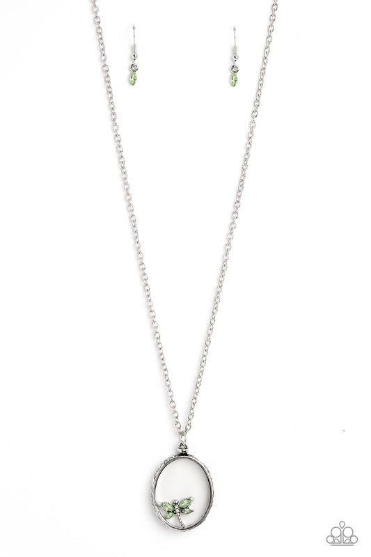 Paparazzi Accessories Dynamic Dragonfly - Green Falling from a high-sheen silver chain, a thick oval pendant with a faceted clear center lengthens the torso as it swings from the bottom of the chain. Swinging from the center of the shimmery pendant, an in