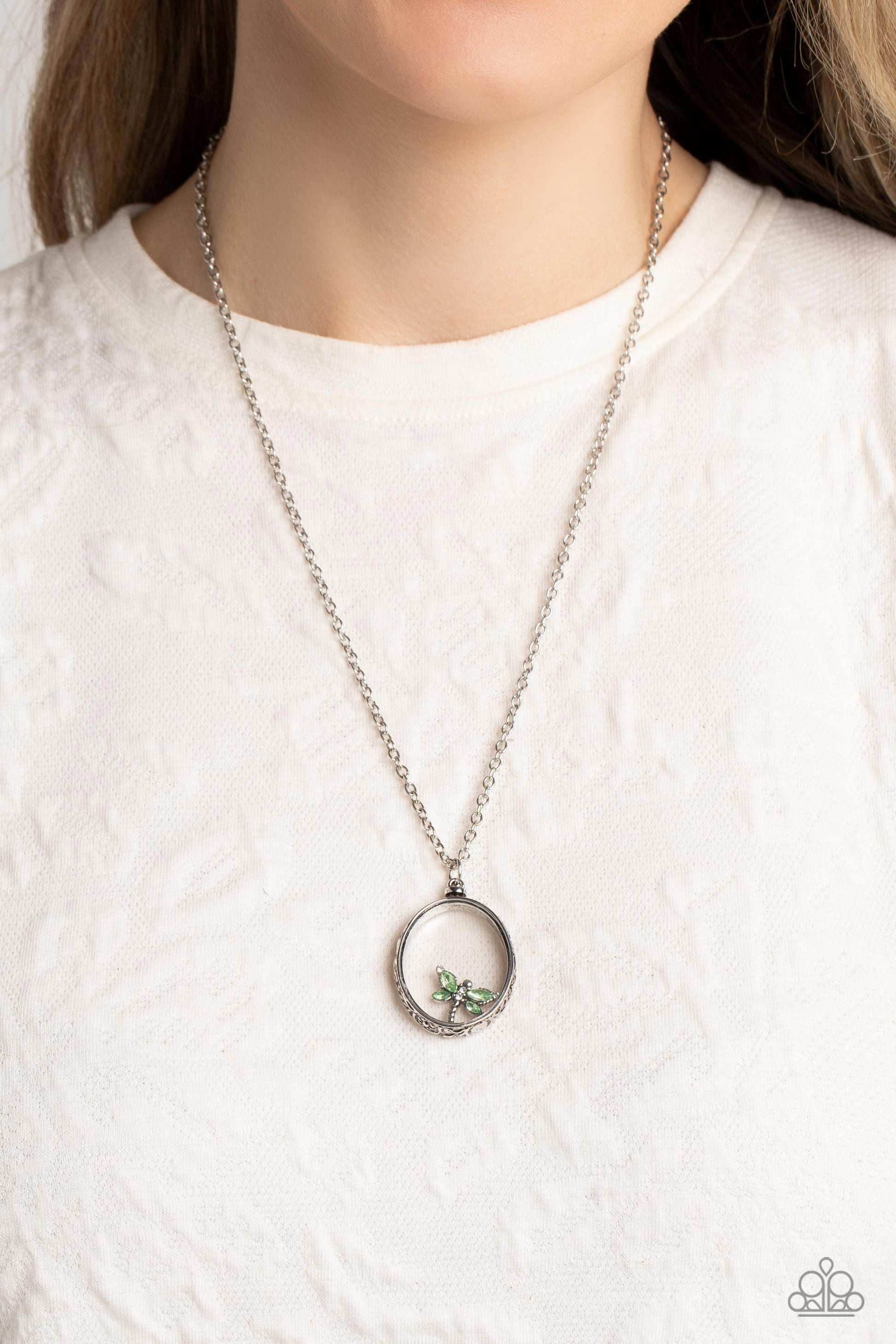 Paparazzi Accessories Dynamic Dragonfly - Green Falling from a high-sheen silver chain, a thick oval pendant with a faceted clear center lengthens the torso as it swings from the bottom of the chain. Swinging from the center of the shimmery pendant, an in