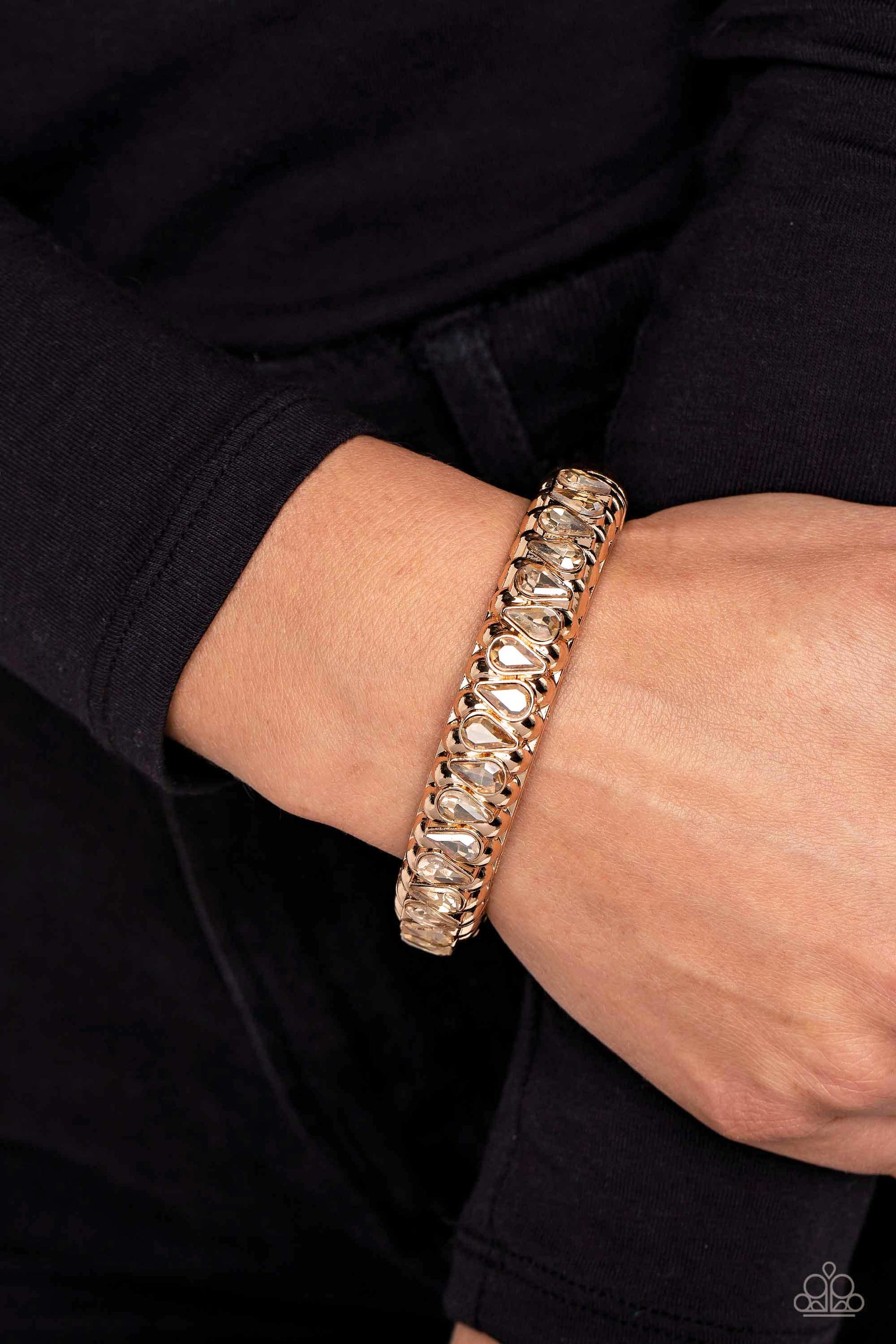 Paparazzi Accessories Crafted Coals - Gold A thick band of gold is embossed in a teardrop-shaped texture, as it wraps around the wrist to create a bold bangle with a hinged closure. A shock of sparkle adorns one side of the design, as glamorous teardrop-s