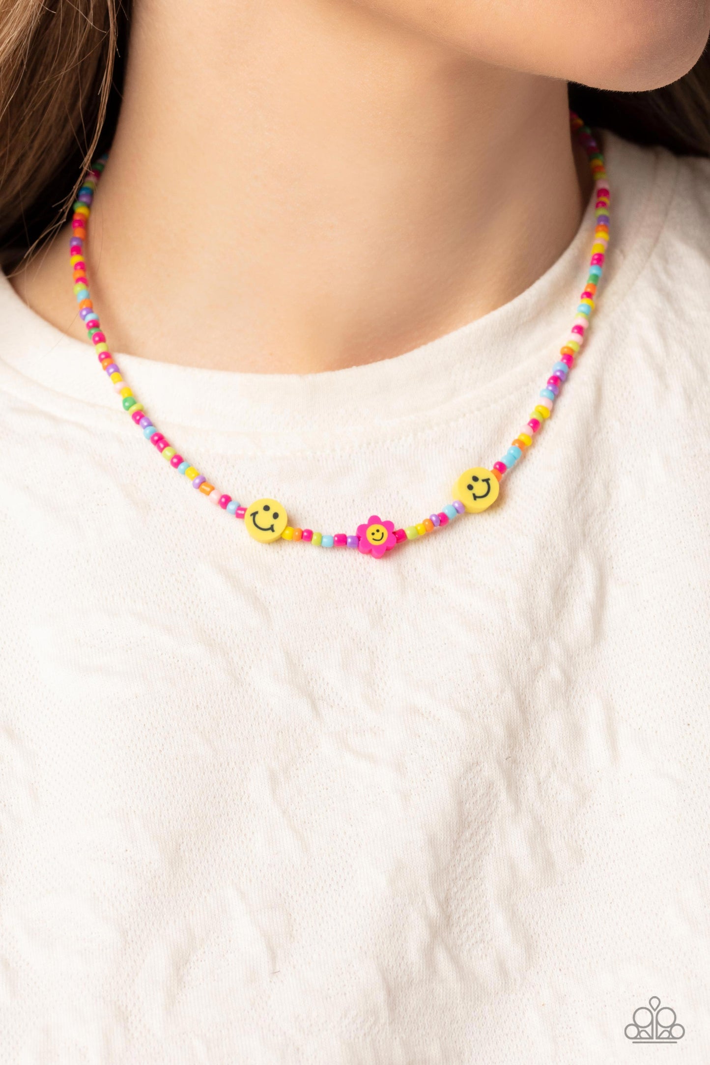 Paparazzi Accessories Flower Power Pageant - Pink Bright colorful seed beads are threaded along a wire, falling along the collar in a capricious pattern. Bringing additional charm to the design, yellow smiley face beads, and a pink flower with a yellow sm
