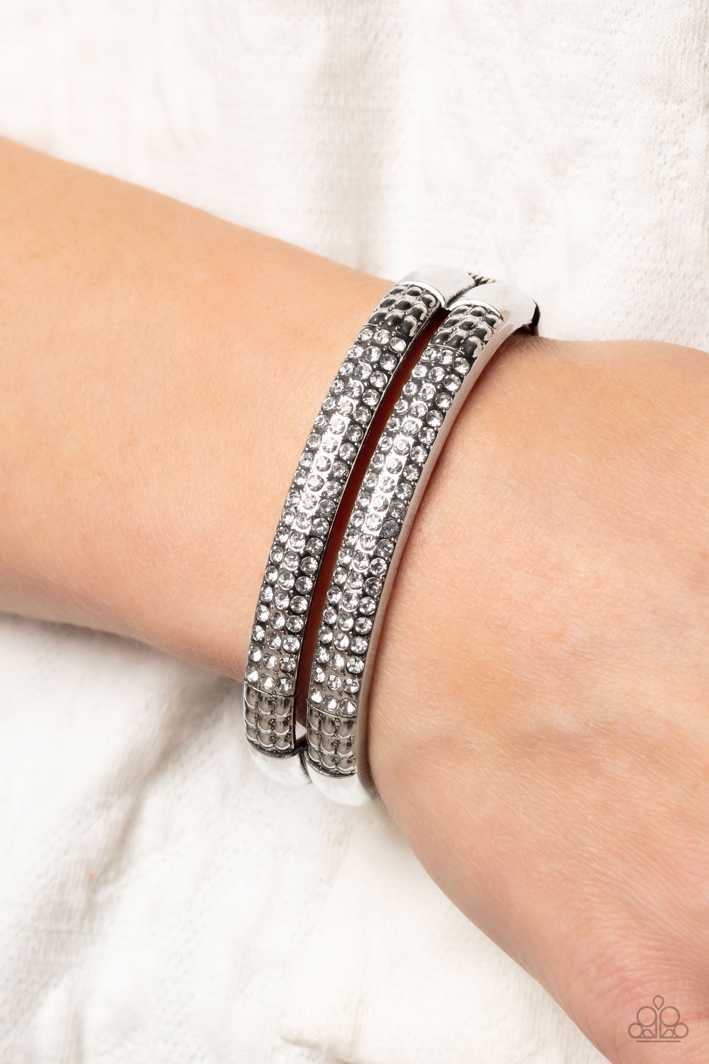 Paparazzi Accessories STACKED Up - White Three rows of dainty white rhinestones are encrusted along two thick silver layers as they stack upon the wrist. Rows of studded silver in a dot-motif border the glittery design for additional texture on the indust