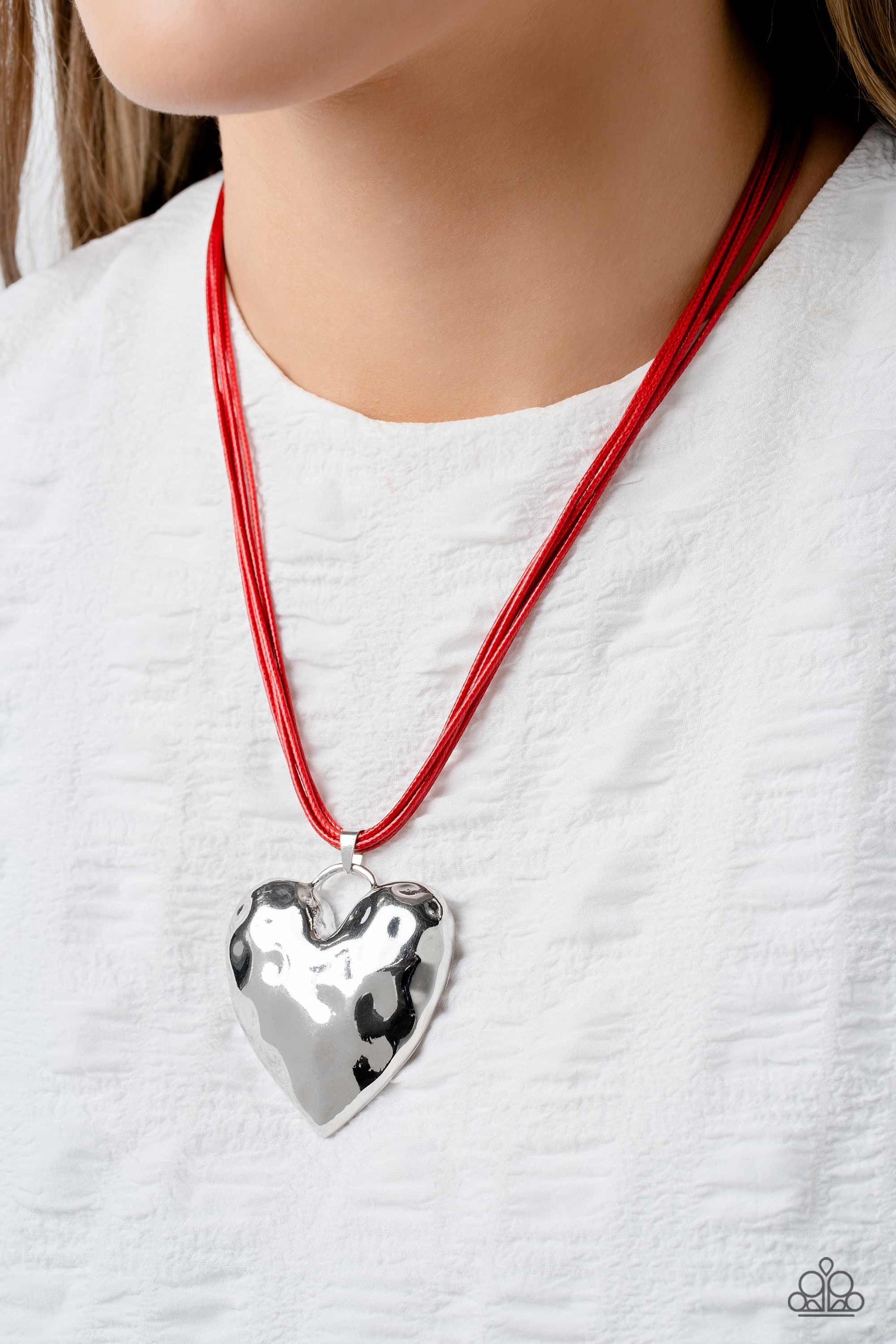 Paparazzi Accessories Confident Courtship - Red An oversized, silver heart pendant featuring a hammered sheen, falls down the neckline at the end of red cording for an alluring appeal. Features an adjustable clasp closure. Sold as one individual necklace.