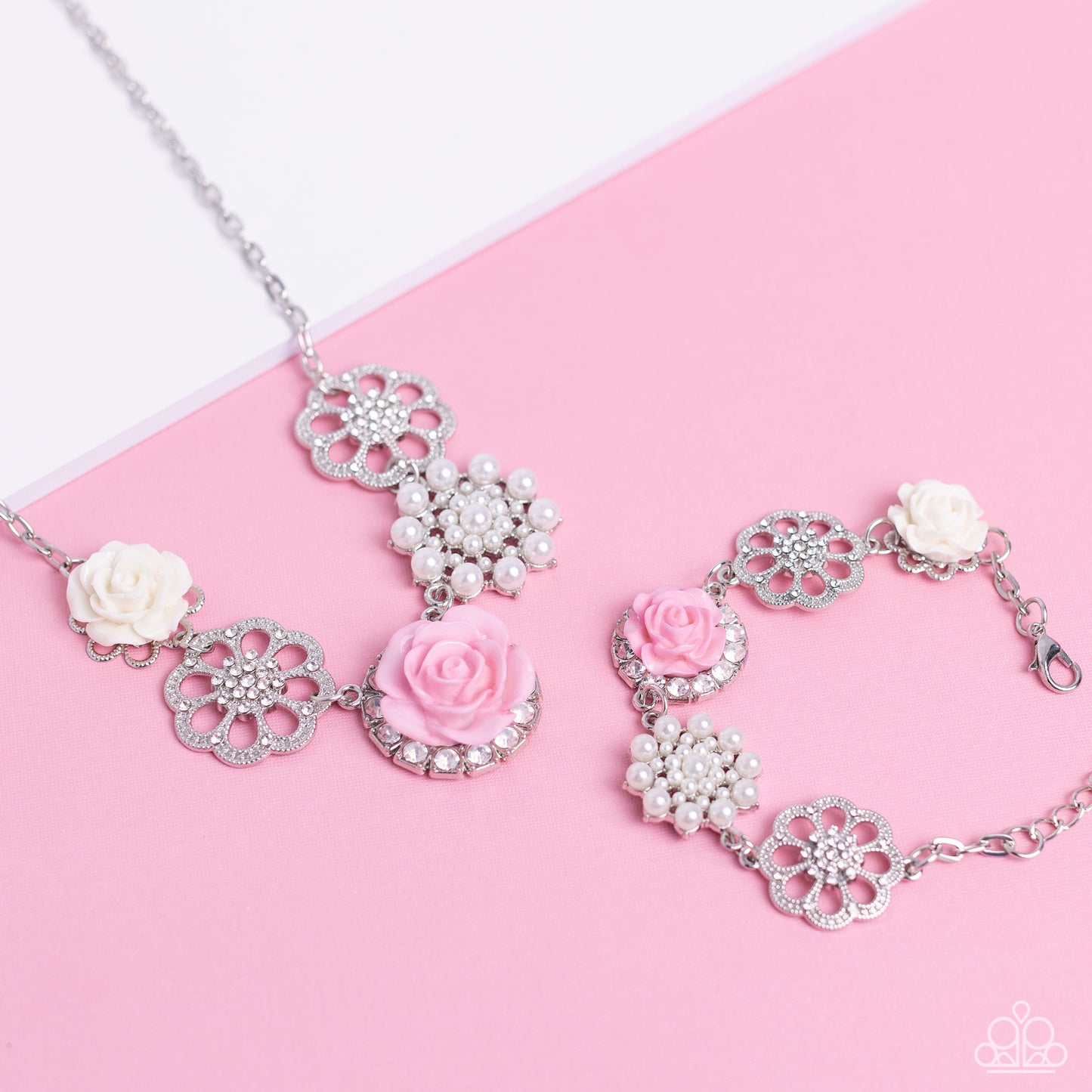 Paparazzi Accessories Tea Party Theme - Pink A collection of whimsical, refined flowers gathers along a flat, sleek silver link chain. The featured charms include an ivory resin rose blooming atop a glittery silver floral silhouette, two silver flowers du