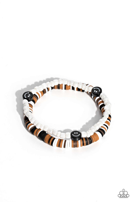 Paparazzi Accessories Tabloid Talent - Black Black, tan, white, and brown clay discs combine with a strand of white seed beads to provide a vibrant pop of color along the wrist. Sporadically dotted in the high-sheen seed bead strand, black smiley face bea