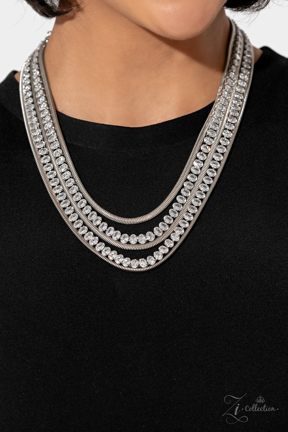 Paparazzi Accessories Tenacious - White Flat, silver snake chains alternate with rows of explosive sparkle, layering into a dynamic lineup of grit and glitz. The meticulous placement and uniform sizing of the glittery, white rhinestones are contrasted by