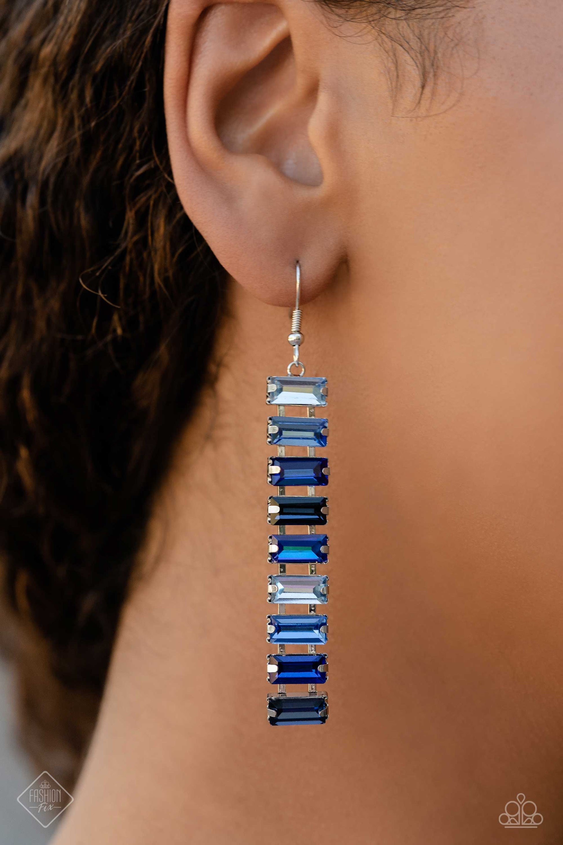Paparazzi Accessories Superbly Stacked - Blue Set in pronged silver fittings, a glassy collection of emerald-cut gems in varying shades of blue fall in line from the ear, creating a stunning, light-catching lure. Earring attaches to a standard fishhook fi
