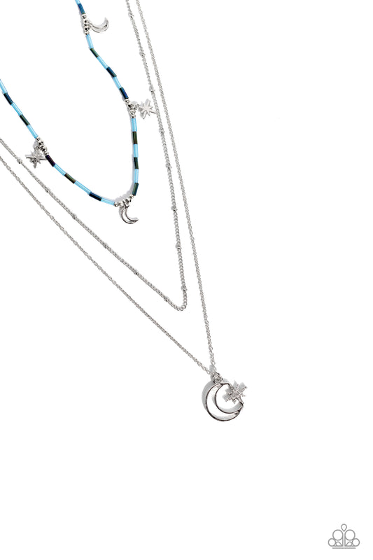 Paparazzi Accessories Constant as the Stars - Blue Three delicate chains cascade in various lengths across the chest, creating a radiantly layered display. Alternating between light blue and oil spill glass beads, a cosmic collection of silver stars and c