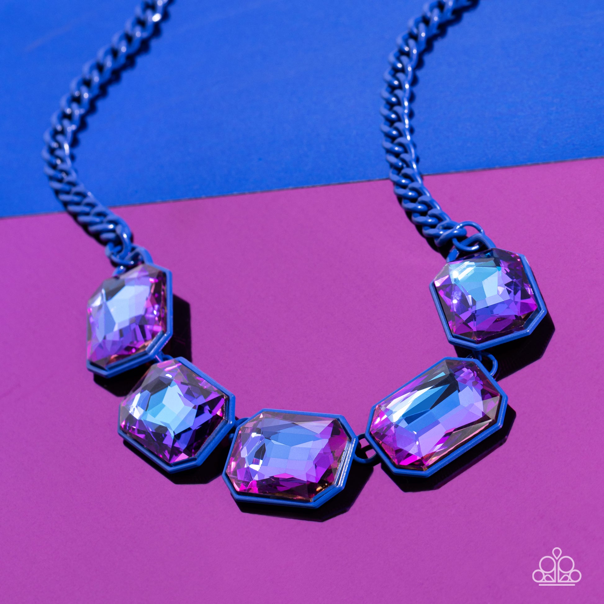 Paparazzi Accessories Emerald City Couture - Blue Featuring a vivacious blue chain, a collection of purple UV shimmery emerald-cut gems, pressed in vibrant blue frames, coalesces around the collar to create a playful pop of edgy color. Features an adjusta